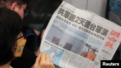 Una mujer lee un periódico sobre China anunciando simulacros militares en Taiwán en la portada mientras viaja en un tren en Taipei, Taiwán, 24 de mayo de 2024. REUTERS/Ann Wang