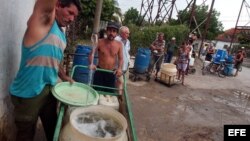 ARCHIVO. Varias personas con cubos y tanques hacen cola en un "Punto de agua".