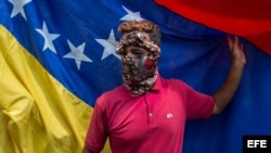 Una manifestante encapuchada durante una marcha en homenaje a un estudiante muerto durante una protesta en Caracas. (Archivo)