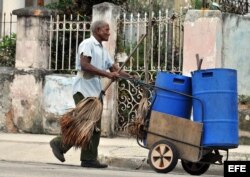 Un anciano barrendero camina por una calle en La Habana.