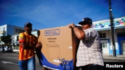 Dos residentes de La Habana cargan un refrigerador adquirido en una tienda recuadadora de divisas. (REUTERS/Alexandre Meneghini).
