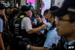 La policía registra a una mujer (C) en el distrito de Causeway Bay de Hong Kong el 4 de junio de 2024 en busca de indicios de recuerdo de su 35º aniversario. (Foto de ISAAC LAWRENCE / AFP)