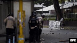 Un grupo de manifestantes se defienden de la policía durante una protesta