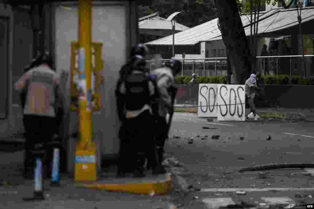 Un grupo de manifestantes se defienden de la policía durante una protesta