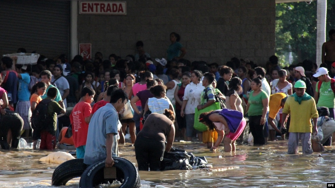 Personas cargan productos saqueados a tiendas hoy en el puerto de Acapulco (México), tras el paso del huracán Manuel