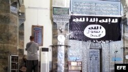 Un hombre reza en la mezquita de Al-Noori Al-Kabeer, junto a una bandera del grupo yihadista Estado Islámico (EI) en Mosul, Irak.
