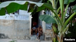 Carmen Guzmán y su esposo José Fleites conversan en la puerta de su casa frente a árboles de plátano que crecen en una calle de La Habana, Cuba, el 12 de febrero de 2025. REUTERS/Norlys Pérez