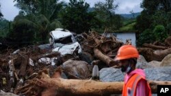 Un rescatista camina entre árboles arrancados de raíz y escombros en Chooralmala, distrito de Wayanad, estado de Kerala, India, el miércoles 31 de julio de 2024. (Foto AP/Rafiq Maqbool)