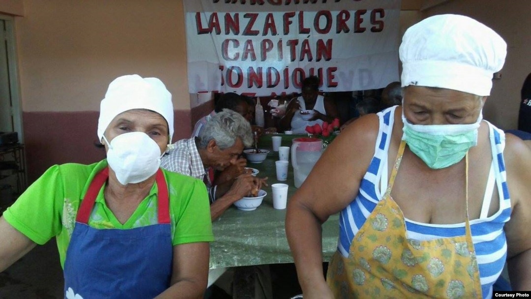 Dos mujeres del proyecto "Capitán Tondique" sirven alimentos en un almuerzo a desamparados en Matanzas.