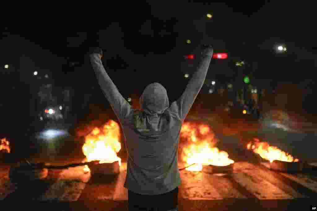 Un manifestante levanta los brazos frente a neumáticos en llamas en Caracas, Venezuela, el lunes 29 de julio de 2024, un día después de las elecciones presidenciales. (Foto AP/Matías Delacroix)