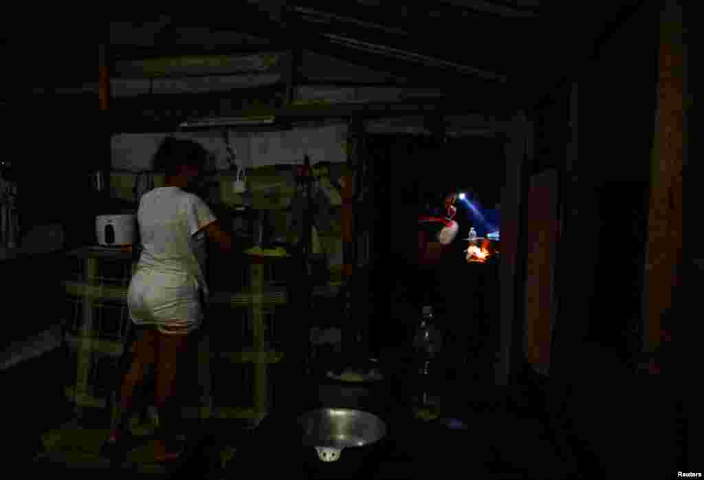 Deysys Fleitas, de 20 años, prepara la comida mientras su esposo, el pescador Yudel Ramos, de 30 años, aviva el fuego en una cocina de leña durante un apagón, en Palpite, Ciénaga de Zapata, Cuba, el 7 de abril de 2026. REUTERS/Norlys Perez