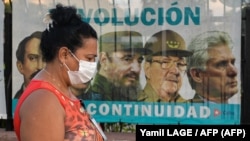 Una mujer en La Habana camina en medio de la pandemia, frente a un cartel con propaganda del gobierno autoritario de partido único (Yamil LAGE / AFP).
