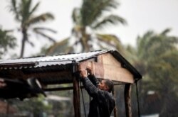 Campesino intenta asegurar techo de su cobertizo de los embates del huracán Eta