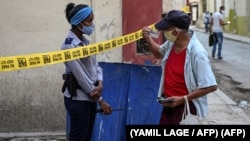 Una oficial de policía exige identificación a un ciudadano en una calle de La Habana cerrada por coronavirus. (YAMIL LAGE / AFP)