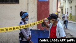 Una oficial de policía exige identificación a un ciudadano en una calle de La Habana cerrada por coronavirus. (YAMIL LAGE / AFP)