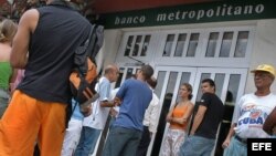 Varias personas hacen colas en un Banco de La Habana. 