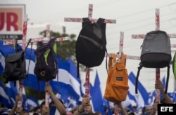 Jóvenes sostienen cruces con mochilas en honor a los estudiantes que murieron en las protestas contra Ortega.