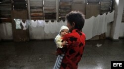 Una mujer carga un bebé en un albergue en el municipio de La Coloma, provincia de Pinar del Río. 