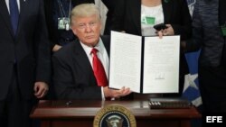  El presidente estadounidense, Donald J. Trump (c), enseña la firma de la orden ejecutiva para destinar fondos federales a la construcción del muro con México durante una ceremonia en el Departamento de Seguridad Nacional en Washington, Estados Unidos, ho