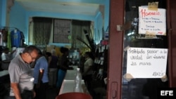 Varias personas observan productos dentro de una tienda, donde se puede ver un cartel alusivo al control sanitario hoy, martes 15 de enero del 2013, en la capital cubana. El Gobierno de Cuba informó de que se han confirmado hasta ahora 51 casos de cólera 