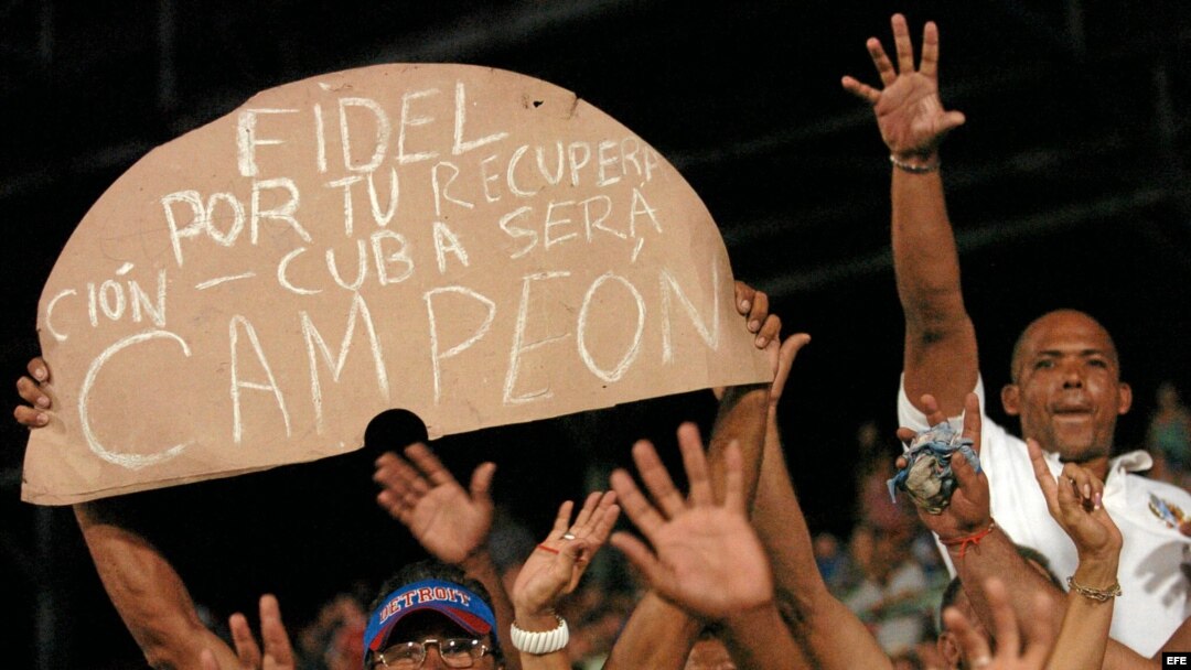 Aficionados cubanos muestran un cartel de adhesión a Fidel Castro.