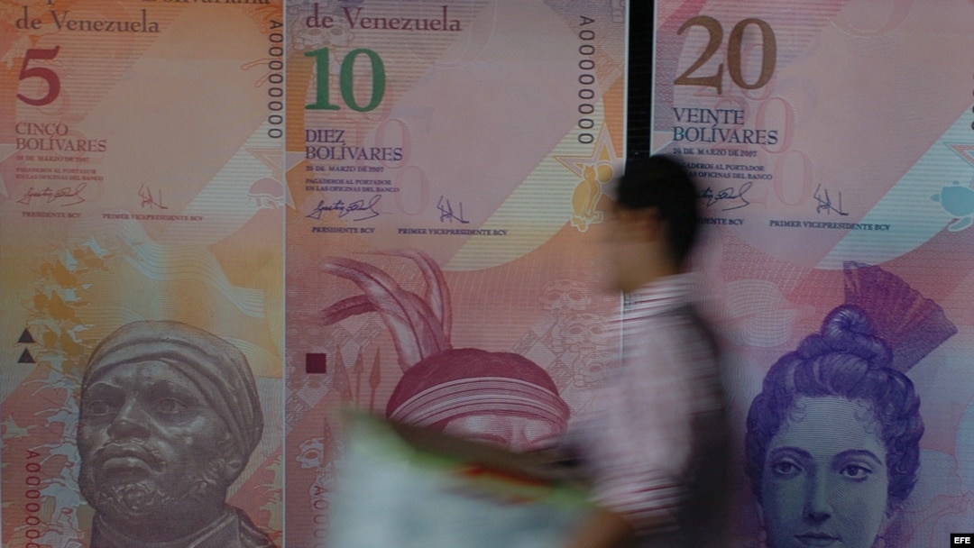 Un hombre pasa frente a varios modelos de billetes venezolanos.