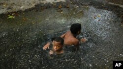 Niños venezolanos bañándose en el agua estancada de la calle
