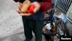 Un hombre sostiene las verduras que encontró en un contenedor de basura en Caracas, Venezuela, el 27 de febrero de 2019.