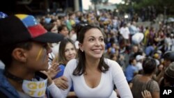 La líder opositora María Corina Machado, una ex legisladora, saluda a sus simpatizantes durante una vigilia en honor a los que han muerto durante enfrentamientos entre las fuerzas de seguridad del gobierno y los manifestantes en Caracas, Venezuela.