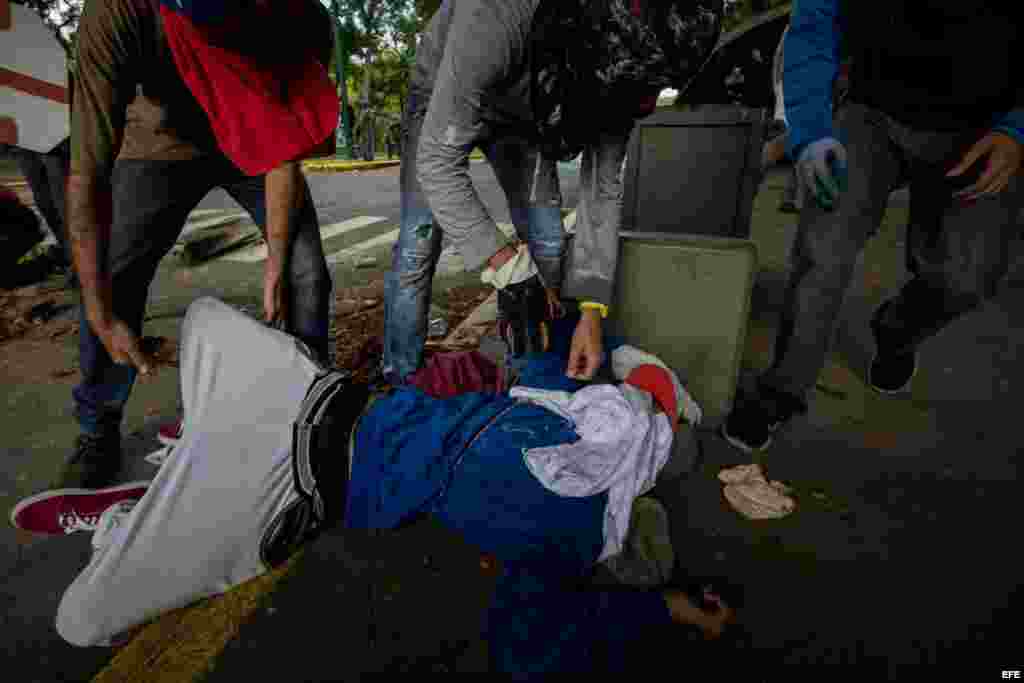Un manifestante recibe ayuda de sus compañeros tras resultar herido durante un enfrentamiento con policías antimotines hoy, jueves 4 de mayo de 2017, en Caracas (Venezuela). Los cuerpos de seguridad dispersaron con gases lacrimógenos la manifestación de e