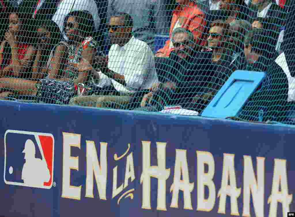 Barack Obama (c), su esposa, MIchelle Obama (3i, y sus hijas, Malia (i) y Sahsa (2i), y el mandatario cubano, Raúl Castro (3d), asisten al juego de béisbol entre el equipo de Cuba y los Rayos de Tampa Bay. 