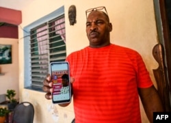 Luis Wilber Aguilar, padre de Wagniel Aguilar —procesado por las protestas antigubernamentales del 11 y 12 de julio—, muestra una fotografía de su hijo en su teléfono móvil en su casa del barrio de La Güinera, en las afueras de La Habana, el 28 de junio de 2022.