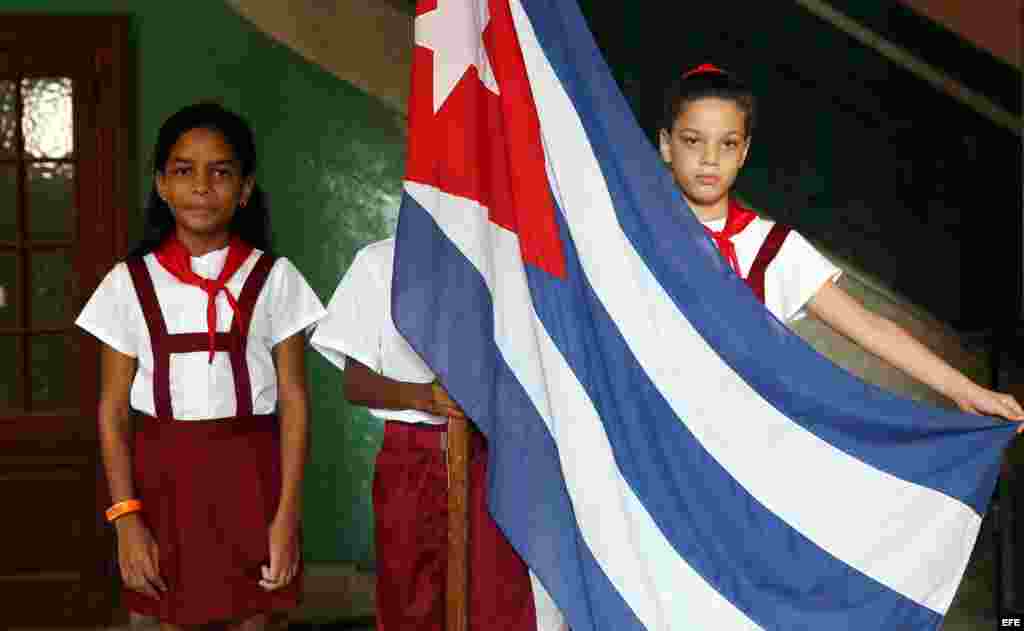 Tres niños posan con una bandera cubana. Cuba comienza este martes, 1ro. de septiembre, el curso escolar 2015-2016 con cerca de dos millones de estudiantes en más de 10.300 escuelas, según cifras oficiales que no describen las dificultades que enfrentarán estudiantes, profesores y padres por la falta de recursos y el déficit de maestros. EFE
