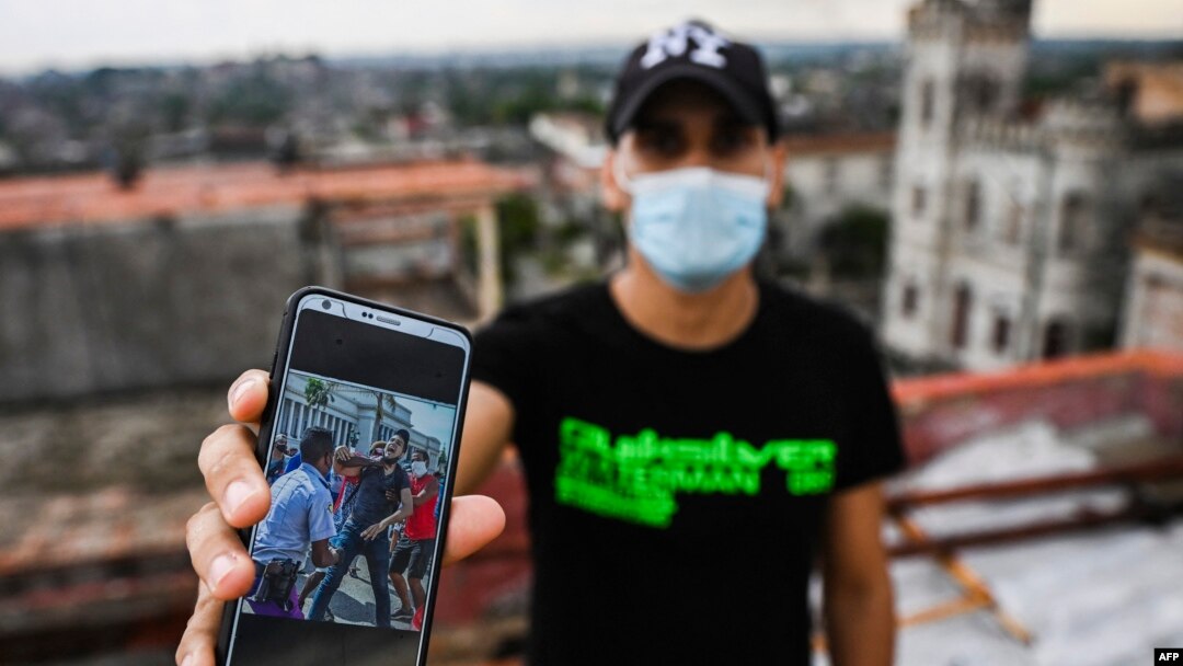 Rolando Remedios muestra una foto en su celular de su arresto durante las protestas del 11 de julio de 2021. (YAMIL LAGE/AFP)