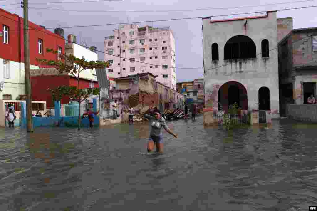 Una mujer cruza una calle inundada por las penetraciones del mar hoy, sábado 23 de enero de 2016, en La Habana (Cuba). EFE/Alejandro Ernesto