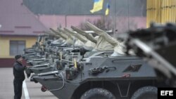 Un soldado ucraniano hace guardia junto a varios vehículos armados en una base militar en Lviv (Ucrania)