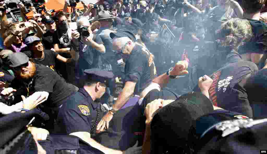 Un grupo de manifestantes es detenido por la policía luego de quemar una bandera de EE.UU. cerca a la entrada a Quicken Loans Arena, sitio donde se realiza la Convención Nacional Republicana.