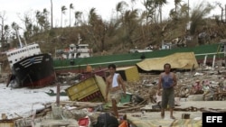 Dos filipinos se abren paso entre los escombros en la devastada ciudad de Tacloban (Filipinas), lunes 11 de noviembre de 2013.