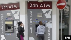 Dos mujeres sacan dinero de un cajero de una sucursal cerrada del Banco de Laiki, en Nicosia, Chipre.