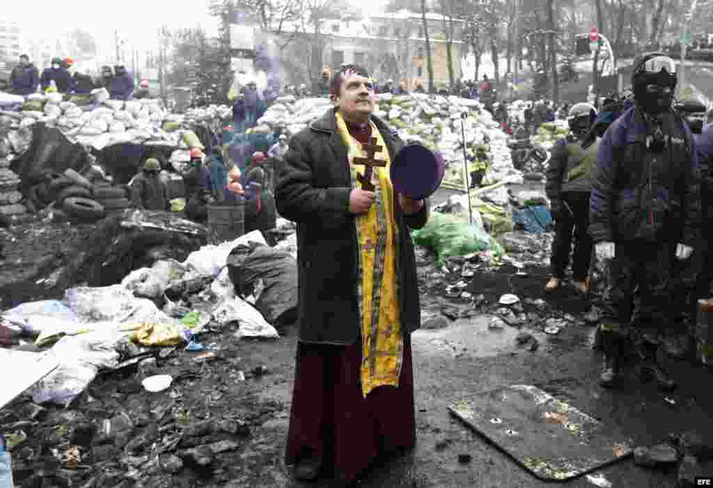 Un sacerdote ucraniano reza ante una barricada en otra jornada de protestas antigubernamentales en Kiev (Ucrania) .