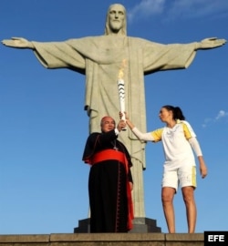 Isabel Barroso entrega la antorcha olímpica al cardenal Orani Tempesta.