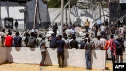 Migrantes observan el sitio impactado en el Centro de Detención de Tajoura en Trípoli.