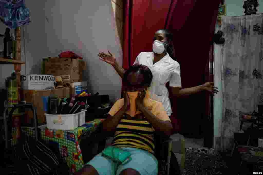 Hairdresser Yulieska Iglesias, wearing a protection mask amid concerns about the spread of the coronavirus disease (COVID-19), gestures after finishing with a client at her home, in Havana, Cuba, March 25, 2020. REUTERS/Alexandre Meneghini