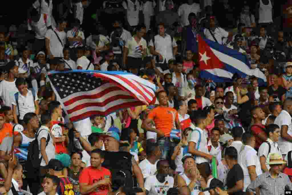 Un aficionado al fútbol porta una bandera cubana, mientras otro hace ondear la estadounidense, en el&nbsp; partido amistoso entre Cuba y Estados Unidos, en el estadio Pedro Marrero en La Habana, donde los visitantes ganaron dos goles a cero. &nbsp;
