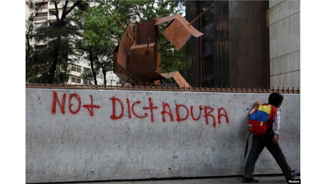 Un niño pasa junto a un graffit contra Nicolás Maduro durante un apagón en Caracas.