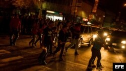 Transeúntes circulan por una calle en la oscuridad durante un corte de energía eléctrica en Caracas (Venezuela). 