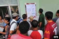 En el 2010 muchos cubanos sacaron licencias para emprender negocios privados. Varias personas leen una cartelera en una oficina municipal de trabajo.