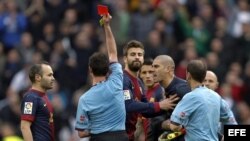 El árbitro Pérez Lasa muestra la tarjeta roja al portero del Barcelona Víctor Valdés (2d) que protesta, mientras su compañero, el defensa Gerard Piqué (3i), intenta frenarlo ante la mirada del centrocampista Andrés Iniesta (i), durante el partido frente a