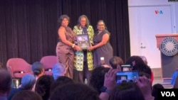 Las sobrinas de Celia Cruz, Celia Cody (izq) y Linda Pritchett (c) reciben las monedas con la imagen de su famosa tía, durante la celebración a la "Reina de la Salsa" en el Museo Nacional de Historia Estadounidense.