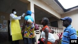 Una enfermera monitorea la temperatura de varias personas en el condado de Bomi, Liberia.